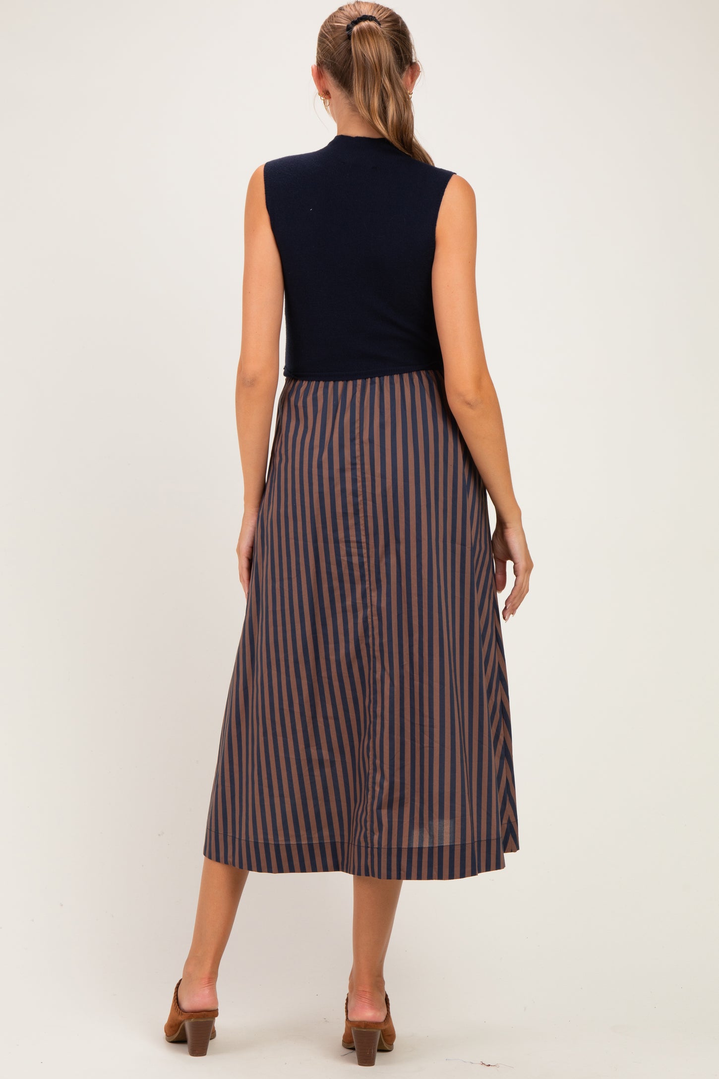woman wearing a navy sleeveless top and a striped midi skirt, showcasing a stylish maternity wear option
