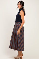woman wearing a navy sleeveless top with a striped midi skirt, styled with a ponytail and beige mules