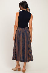 woman wearing a navy sleeveless top and a striped midi skirt, seen from the back, with light brown block heels