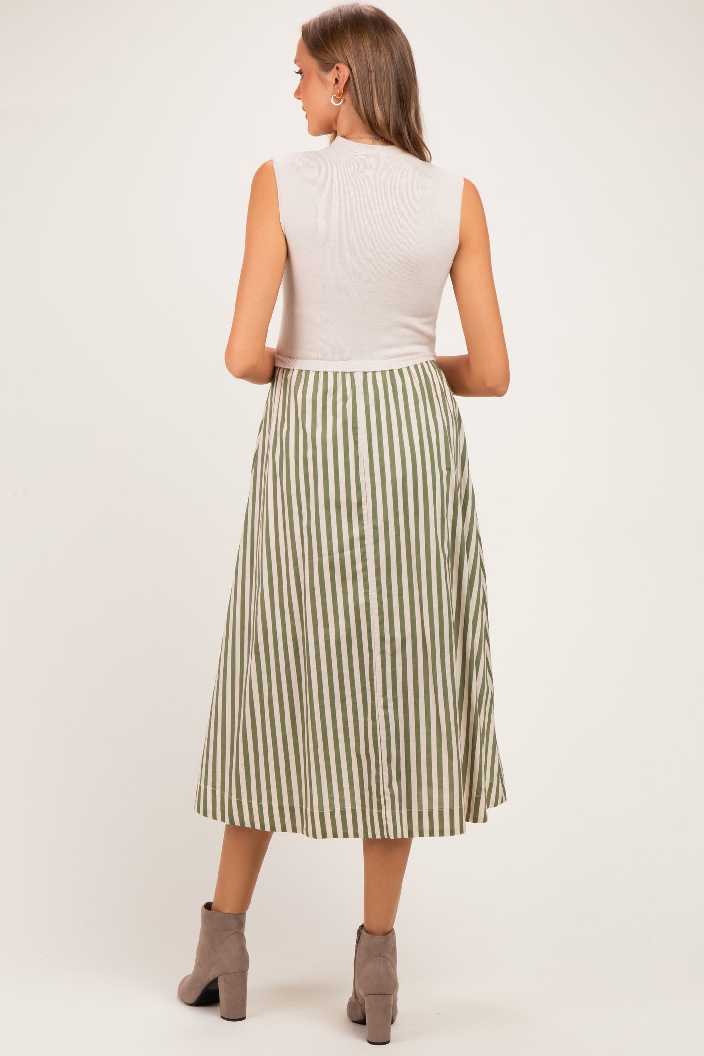 woman wearing a sleeveless white top and a green and white striped maternity maxi skirt, showing a baby bump from behind