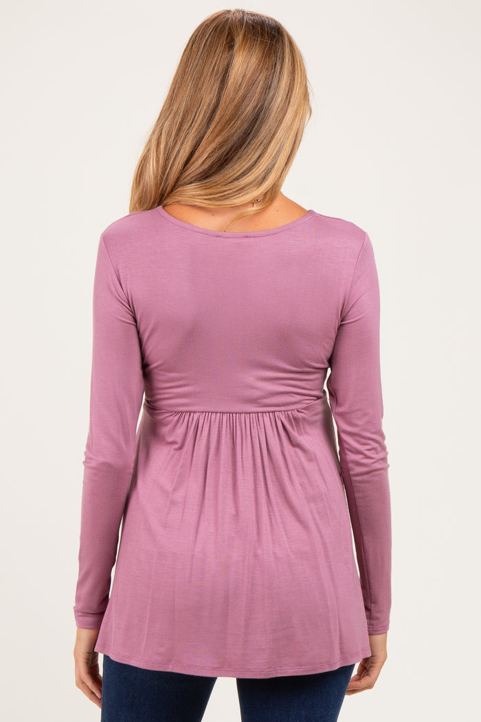 woman wearing a mauve long sleeve maternity top with a cinched waist and flared hem
