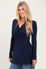woman wearing a navy long sleeve wrap top with a plunging neckline and gathered waistline