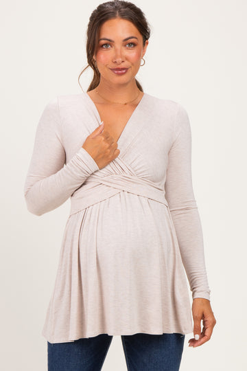 woman wearing a light beige long sleeve maternity top with a wrap style and baby bump visible