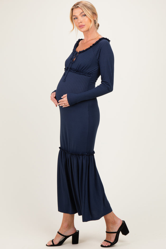 woman wearing a navy blue maternity dress with ruffle details and a visible baby bump