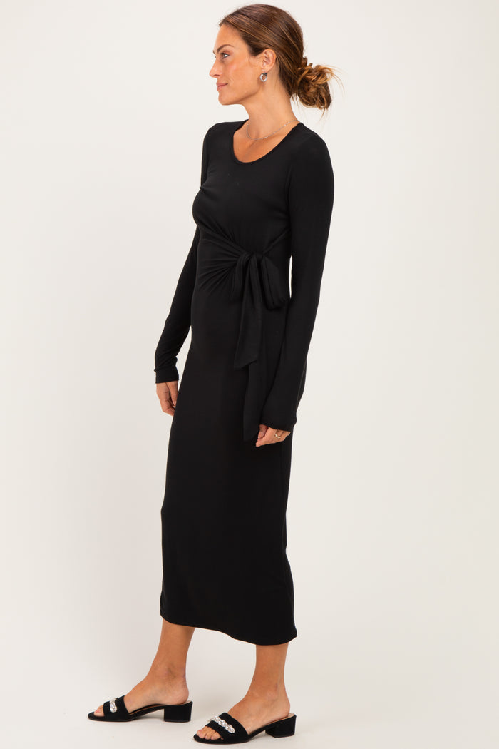 woman wearing a black long sleeve maxi dress with a front tie detail and ankle-length hem