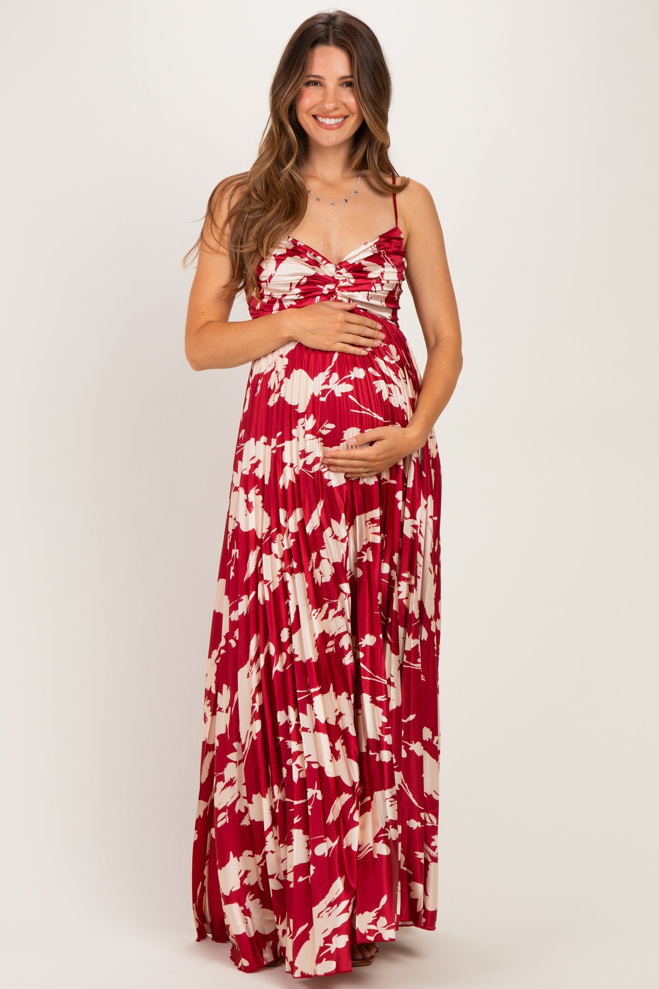 woman wearing a red and white floral maternity maxi dress and holding her baby bump