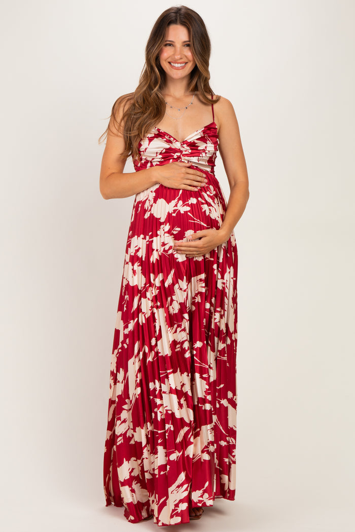 woman wearing a red and white floral maternity maxi dress and holding her baby bump