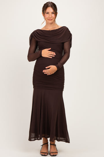 woman wearing a dark brown off-shoulder maternity dress with long sleeves and a fitted bodice, holding her baby bump