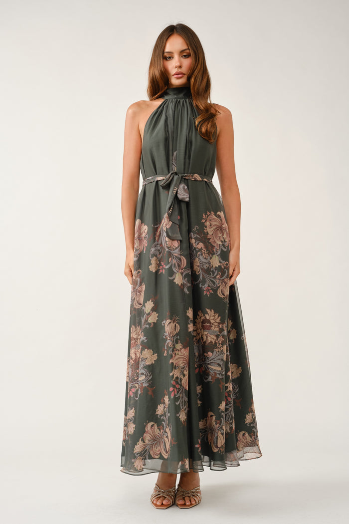 woman wearing a green floral maxi dress with a halter neck and a tied waist belt