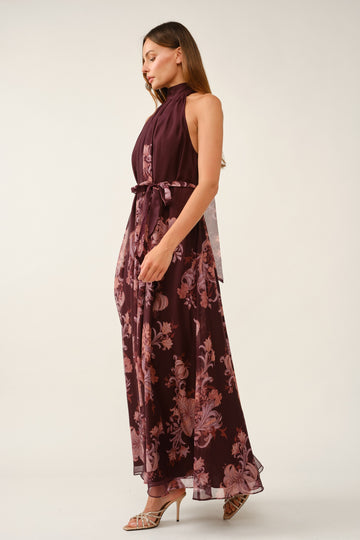 woman wearing a burgundy floral maxi dress with a high neck and tie waist detailing