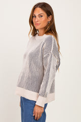 woman wearing a cream and navy striped sweater with a relaxed fit and dropped shoulders paired with blue jeans