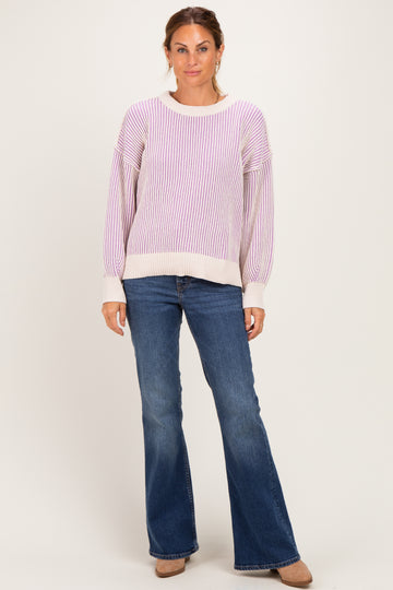 woman wearing a purple and white striped oversized sweater and blue flared jeans