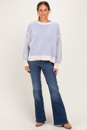 woman wearing a blue and white striped oversized sweater with long sleeves and flared jeans