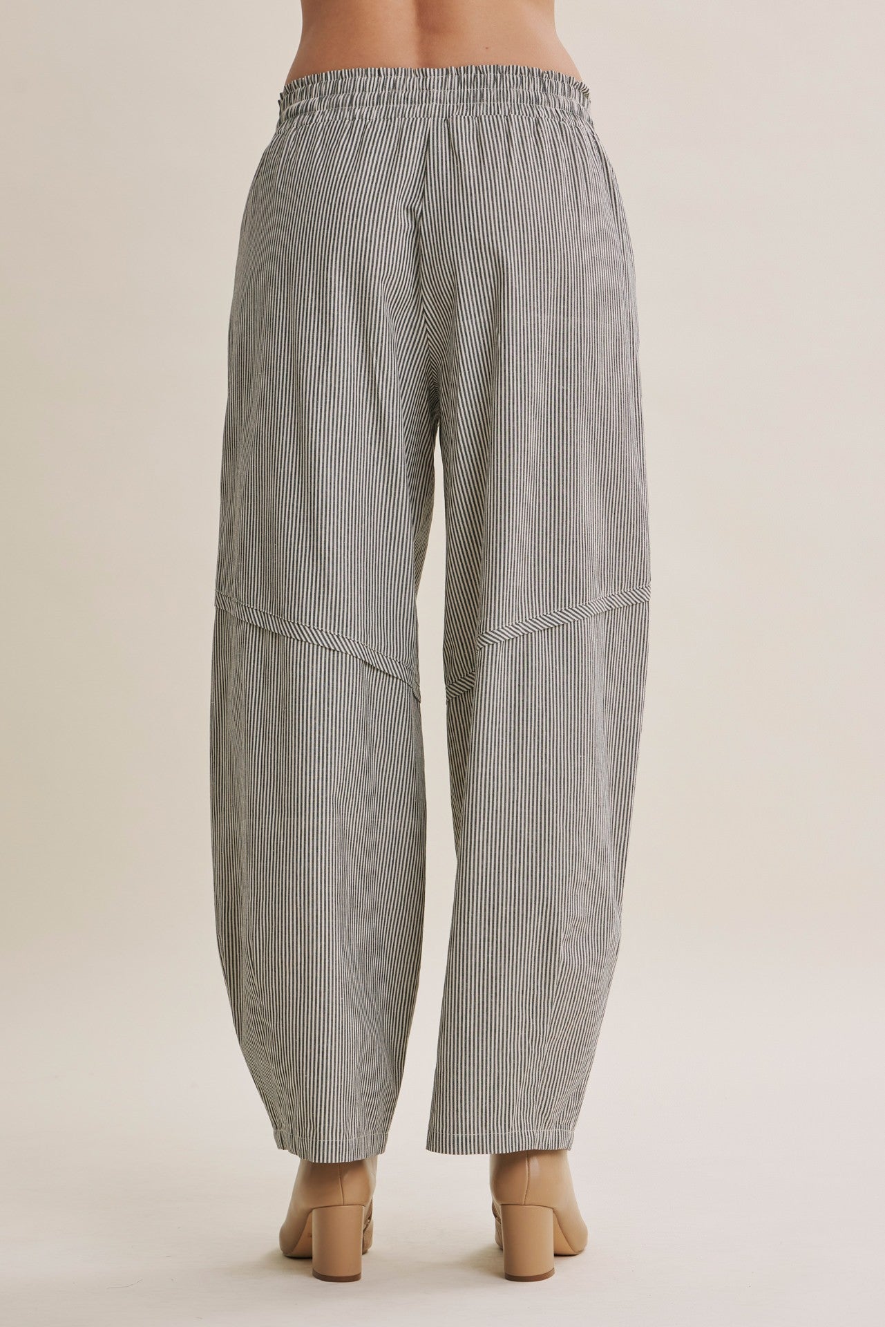 woman wearing black and white striped loose-fitting wide-leg pants, back view