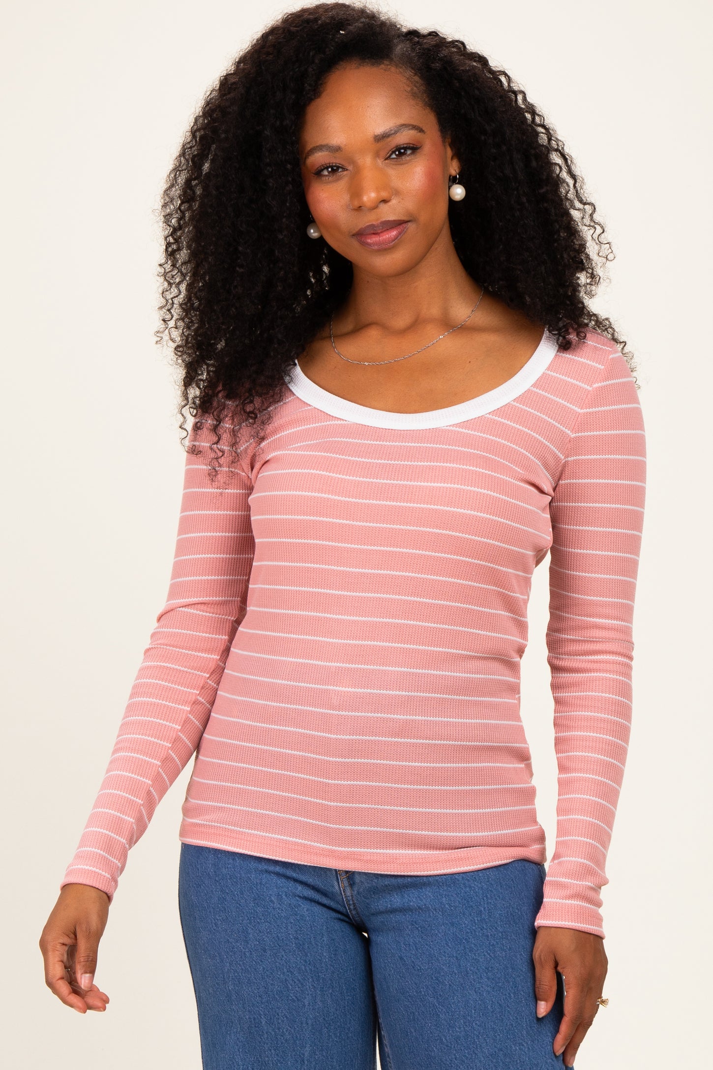 woman wearing a pink and white striped long sleeve top with a scoop neckline and fitted style