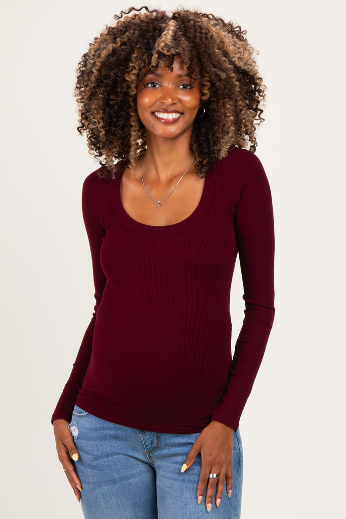 woman wearing a burgundy long sleeve maternity top with a scoop neckline and showing her baby bump