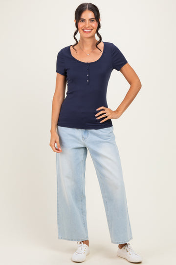 woman wearing a navy blue short sleeve fitted top with button detailing and light wash wide-leg jeans