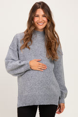 woman wearing a gray maternity sweater with a high neck and long sleeves, holding her baby bump