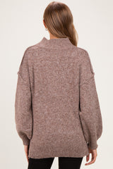 woman wearing a cozy brown maternity sweater with a high neck and balloon sleeves, showing a relaxed fit from the back