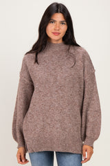 woman wearing a taupe oversized knit sweater with balloon sleeves and a high neckline