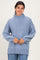woman wearing a light blue oversized knit sweater with a high neckline and loose sleeves