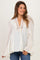 woman wearing a cream maternity blouse with ruffle details and a lace-up neckline, styled with blue jeans