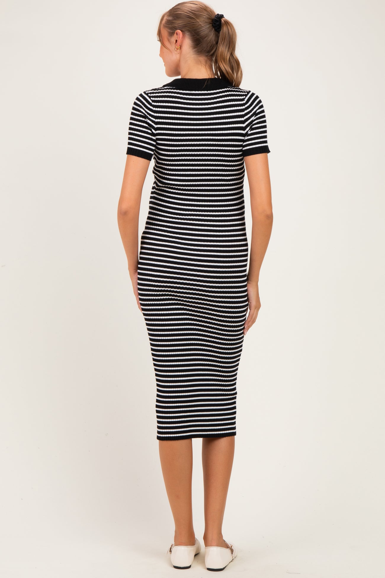 woman wearing a black and white striped maternity dress, seen from the back