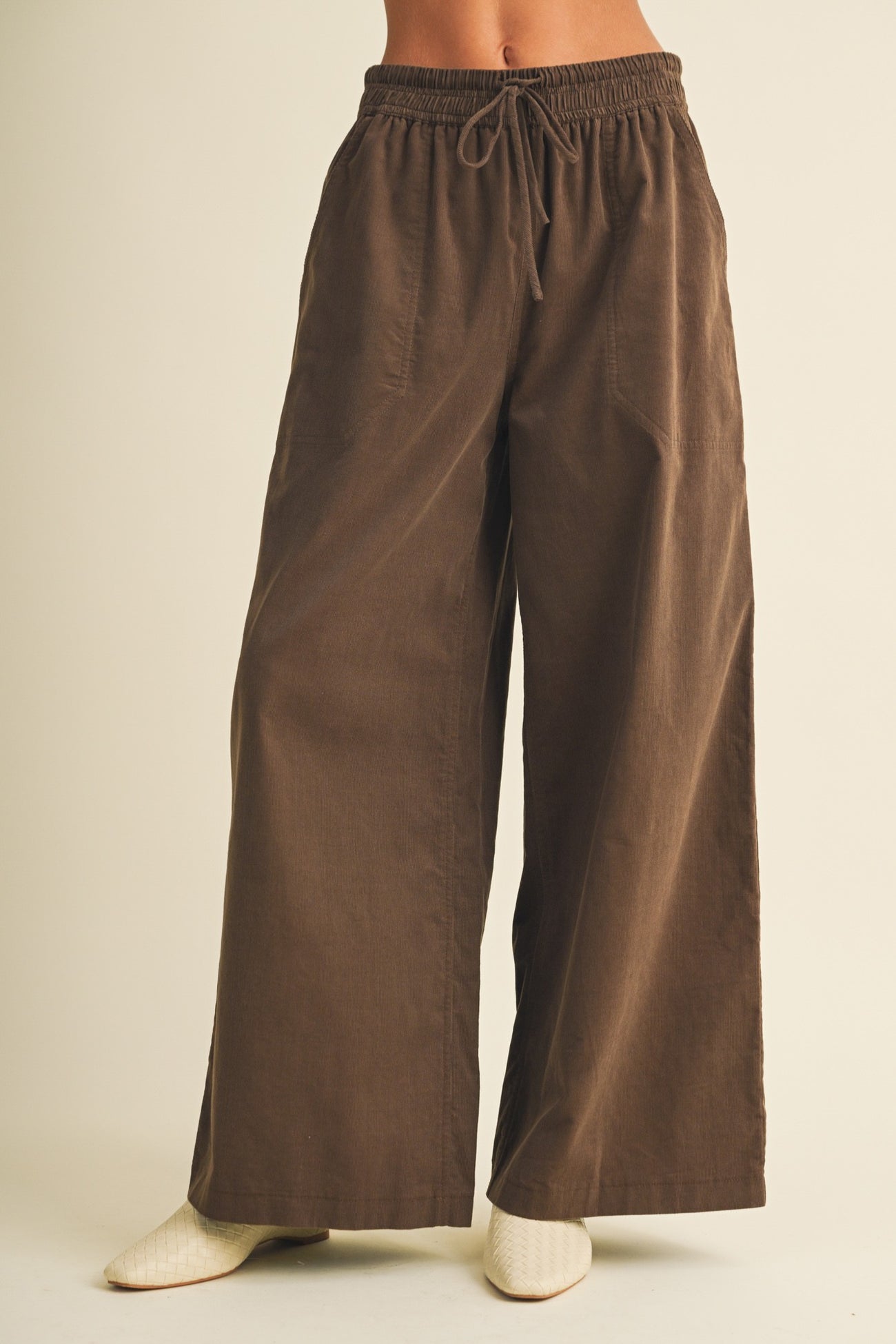 woman wearing brown wide-leg pants with a drawstring waist and side pockets