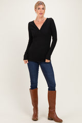 woman wearing a black long sleeve wrap top paired with blue skinny jeans and brown knee-high boots