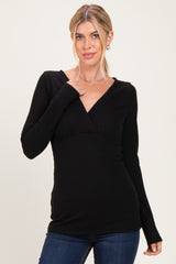 woman wearing a black long sleeve wrap top with a fitted waist and v-neckline
