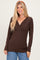 woman wearing a brown long sleeve wrap top with a v-neckline and a fitted silhouette