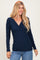 woman wearing a navy long sleeve wrap top with a fitted bodice and v-neckline, styled with casual jeans