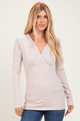 woman wearing a light pink long sleeve v-neck top with a fitted waist and loose hem, styled with a headband