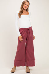 woman wearing a white long sleeve maternity top and burgundy wide-leg maternity pants with pockets and a drawstring