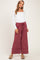 woman wearing a white long sleeve maternity top and burgundy wide-leg maternity pants with pockets and a drawstring