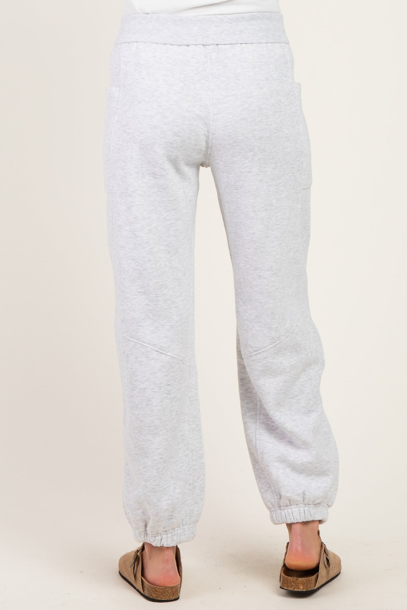 woman wearing gray maternity jogger pants with elastic waistband and ankle cuffs, showing the back view