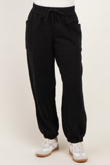 woman wearing black jogger pants with side pockets and elastic cuffs, paired with white sneakers