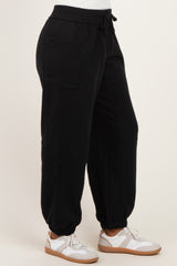 woman wearing black jogger pants with a drawstring waist and side pockets, paired with white sneakers