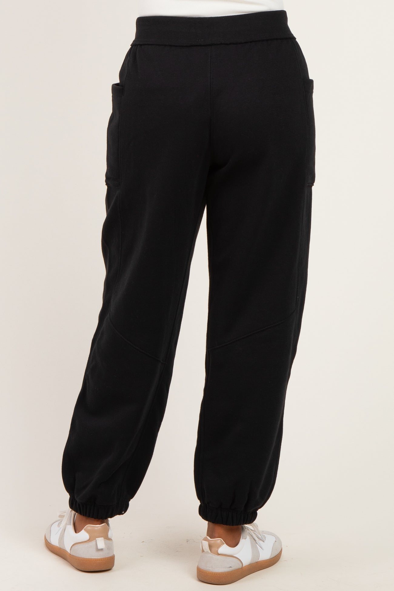 woman wearing black jogger pants with elastic cuffs and side pockets, styled with white sneakers