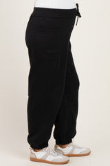woman wearing black maternity joggers with side pockets and ankle cuffs, paired with white sneakers