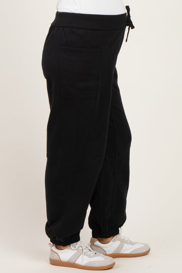 woman wearing black maternity joggers with side pockets and ankle cuffs, paired with white sneakers