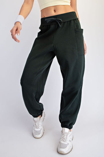 woman wearing dark green jogger pants with a relaxed fit and elastic ankle cuffs, styled with a fitted crop top