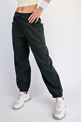 woman wearing dark green jogger pants with side pockets and elastic cuffs, paired with white sneakers