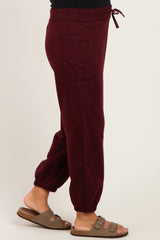maternity wear burgundy jogger pants with elastic cuffs and drawstring waistband, model wearing sandals