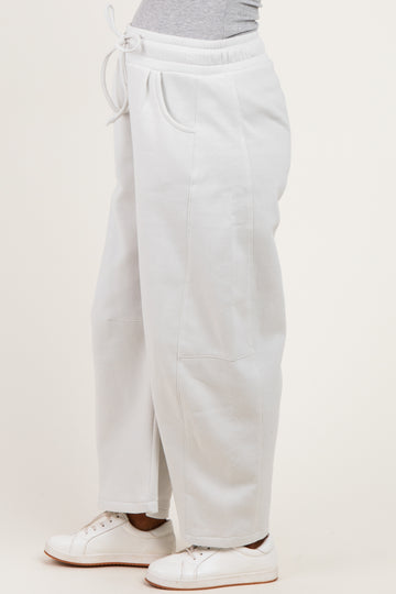 woman wearing light gray maternity sweatpants with a drawstring waist and side pockets.
