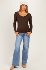 woman wearing a brown long sleeve maternity top with a scalloped neckline and blue flared jeans, no baby bump visible