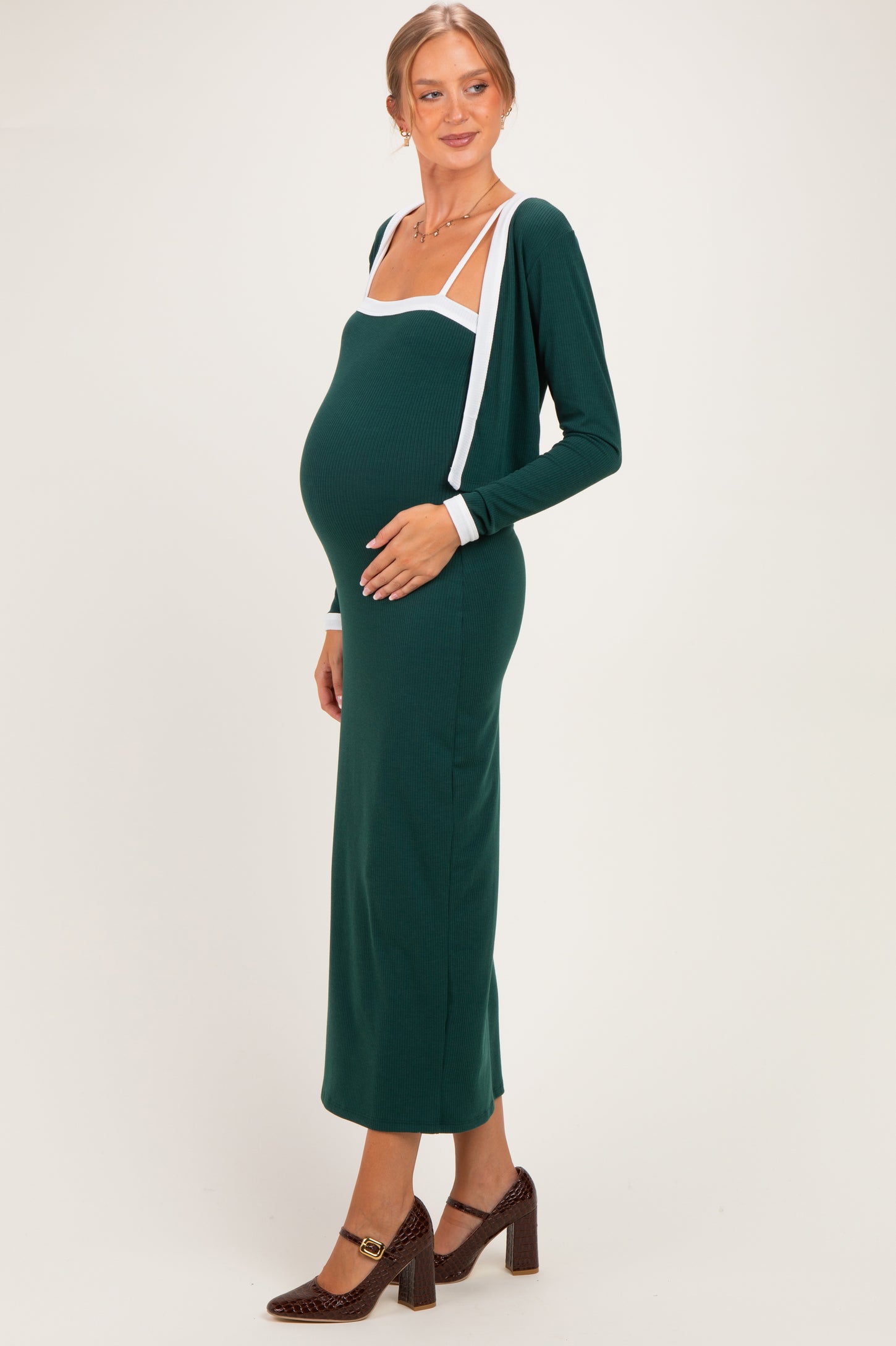 woman wearing a dark green maternity dress with white accent details and a visible baby bump