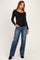 woman wearing a black long sleeve maternity top with scalloped edges and blue wide-leg jeans, showing her baby bump