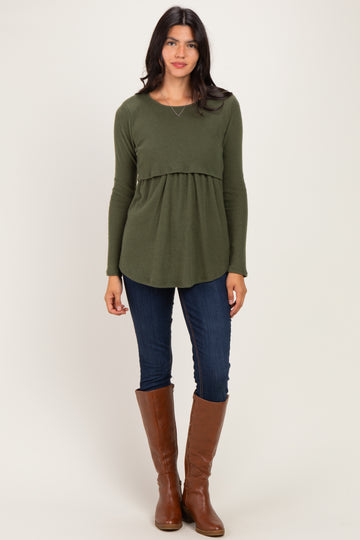 woman wearing an olive green peplum top with long sleeves, paired with dark skinny jeans and tall brown boots