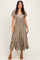 woman wearing a khaki floral midi dress with short sleeves and a v-neckline, standing on beige heels
